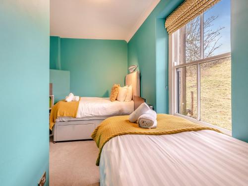 Skye House في بيكويل: سريرين في غرفة بجدران زرقاء ونافذة