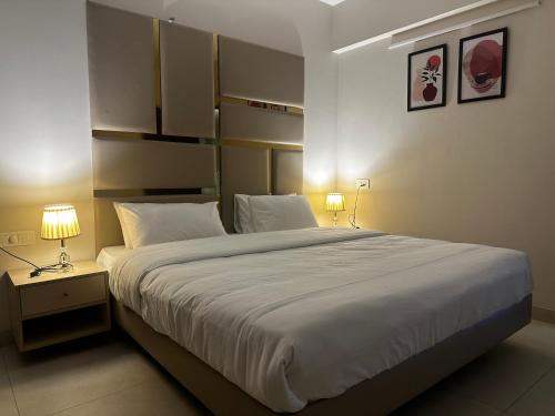 - une chambre avec un grand lit blanc et deux lampes dans l'établissement Celesto Luxury Residences by Chakola’s Hospitality, à Thrissur