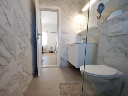a bathroom with a toilet and a walk in shower at Holiday apartman in Kaštela