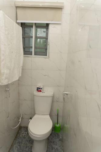 a white bathroom with a toilet and a window at Elegant 1-Bed With Unlimited Starlink SuperFast Speed WiFi & 24hrs POWER in Lagos