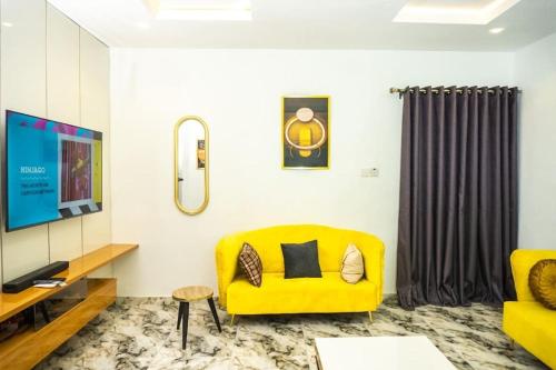 a living room with a yellow couch and a tv at Elegant 1-Bed With Unlimited Internet + 24hrs POWER in Lagos