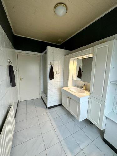 een witte badkamer met een wastafel en een spiegel bij Vakantiehuis Brug24 in Lanaken