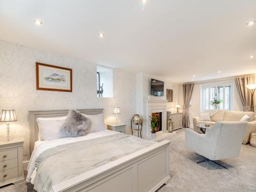 um quarto branco com uma cama e uma cadeira em Shireburn Cottage em Hurst Green
