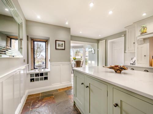 uma cozinha com armários brancos e uma bancada em Shireburn Cottage em Hurst Green