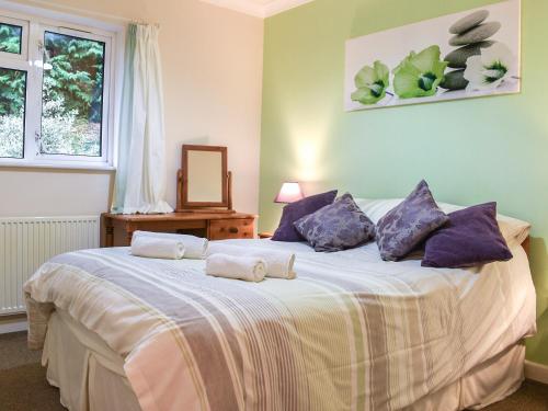 sypialnia z dużym łóżkiem z fioletowymi poduszkami w obiekcie Gwynfan Bungalow w mieście Nantmel