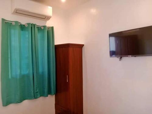 Zimmer mit einem TV und einem grünen Vorhang in der Unterkunft Casi Verde Panglao in Panglao