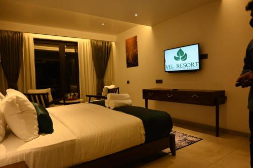 a hotel room with a bed and a tv on the wall at Vee Resort- The Suites of Royals in Mahabaleshwar