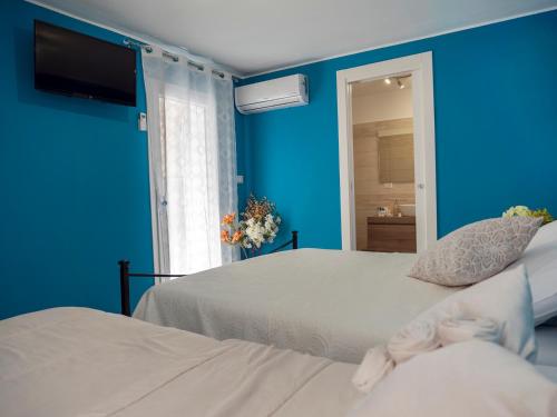 a bedroom with two beds and a blue wall at Flower House in Santo Stefano di Camastra