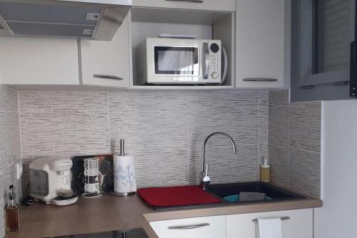 a kitchen with a sink and a microwave at Appartement sur le port d'Arcachon proche plages in Arcachon