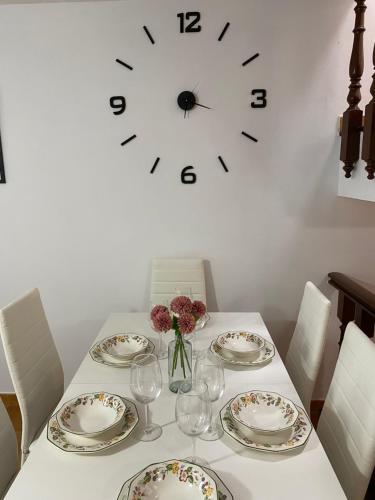 a table with plates and glasses and a clock on the wall at CasaNova in Combarro