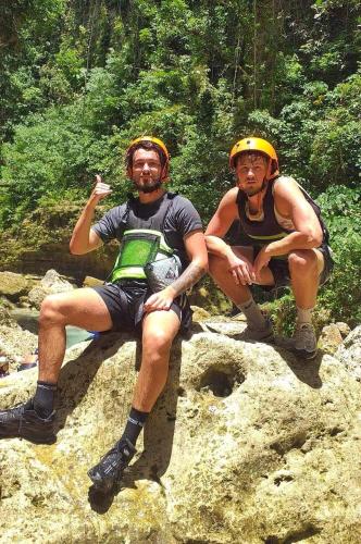 two men sitting on a rock on a trail at House of TamSe Laagans ' Inn in Badian