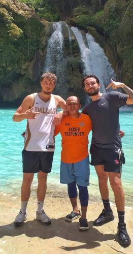 three men standing on a beach in front of a waterfall at House of TamSe Laagans ' Inn in Badian