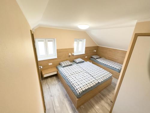 a bedroom with two beds and two windows at Dům v Beskydech – Trojanovice in Trojanovice