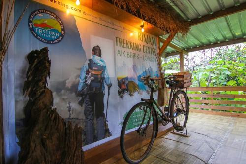 una bicicletta parcheggiata accanto a un muro con un poster di Tastura Homestay a Praya