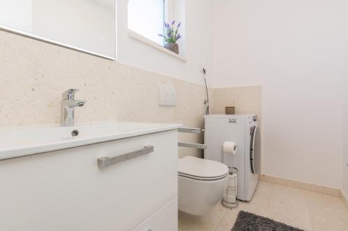a white bathroom with a toilet and a sink at Vila Nena in Vodice