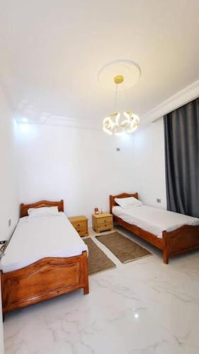 1 dormitorio con 2 camas y lámpara de araña en Villa Line en Taguermess