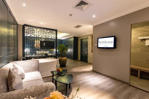 a living room with a couch and a tv on a wall at Silverland Jolie Hotel in Ho Chi Minh City