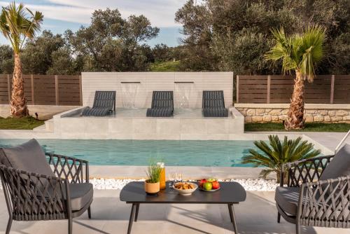 a patio with a table and chairs next to a swimming pool at Villa Silentium Olia by PosarelliVillas in Aryiroúpolis