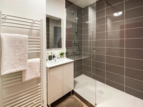 uma casa de banho com um chuveiro, um lavatório e um espelho. em RESIDENCE SWEETLY ISATIS em Mérignac