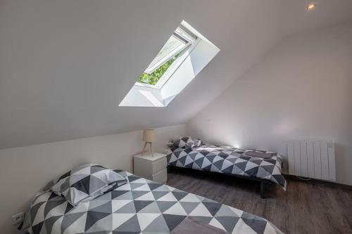 une chambre mansardée avec deux lits et une fenêtre dans l'établissement Le NOUVEAU-LAMALONNIÈRE-HYPERCENTRE-CLOSLUCÉÀ150M, à Amboise