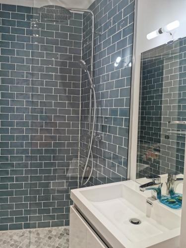 une salle de bain avec un lavabo et une douche avec du carrelage bleu dans l'établissement Chambre meublée indépendante, à Charbonnières-les-Bains