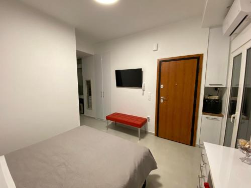 Modern studio apartment B في أثينا: غرفة نوم بسرير ومقعد احمر وتلفزيون