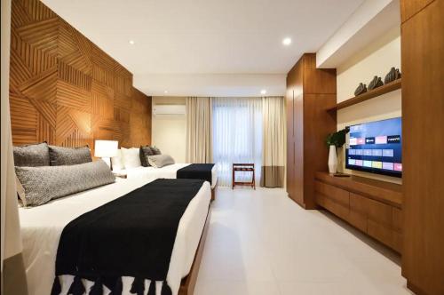 a hotel room with two beds and a flat screen tv at The Apartments at El Nido in El Nido