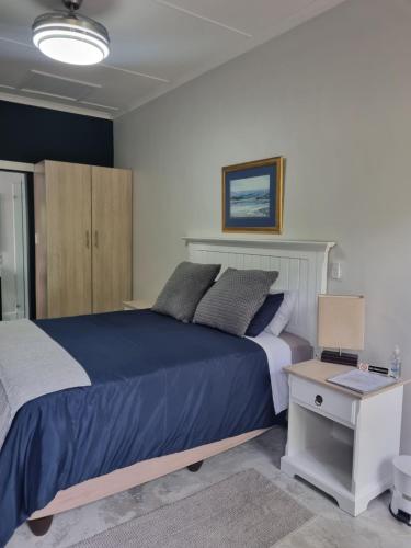 a bedroom with a large blue bed and a desk at 12onParkesLane in Knysna