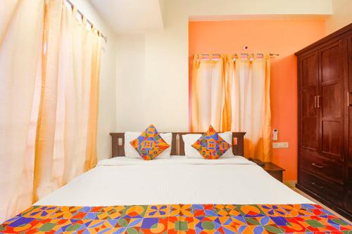 a bedroom with a bed with orange walls and curtains at FabHotel Corner Courtyard in Kondapur