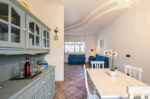 a kitchen and living room with a table and blue chairs at Casa Mary in Fregene