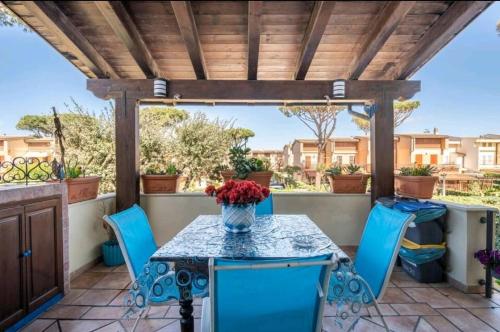 a patio with a table and chairs and a wooden pergola at Casa Mary in Fregene