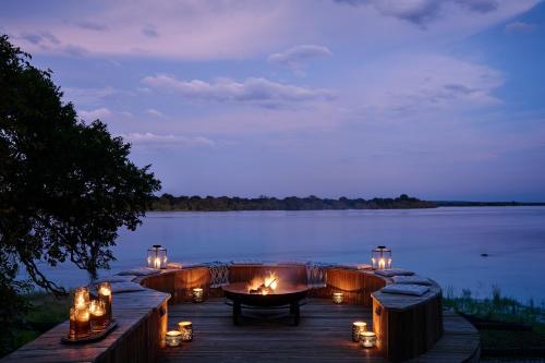 a dock with candles and a lake at night at Victoria Falls River Lodge in Victoria Falls