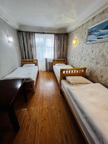 a room with three beds and a window at Khongor Guest house & Tours in Ulaanbaatar