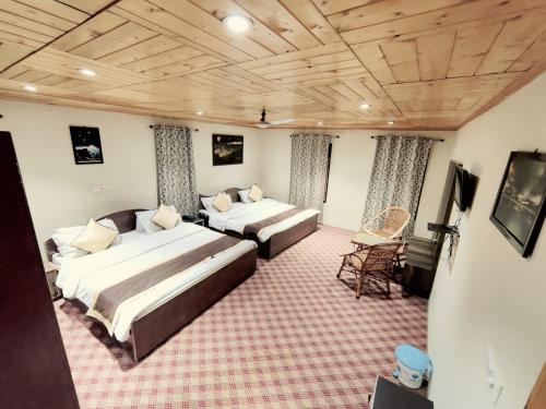 a bedroom with two beds and a television in it at Sheesha Residency in Srinagar