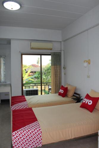two beds in a room with a window at OYO 75420 Howto Hotel in Chiang Mai