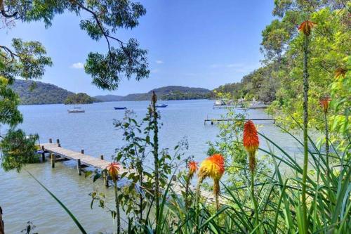 a view of a lake with a dock and flowers at Cosy Cottage Above the Hawkesbury w/ Jetty in Mooney Mooney