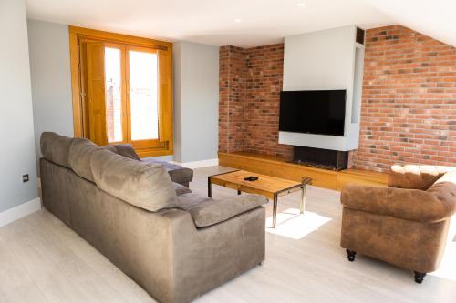 uma sala de estar com um sofá e uma televisão em Principia Suites em León