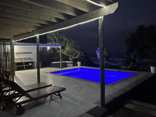 a patio with a bench and a blue pool at night at Linga Futhi Beach Cottages in Port St Johns