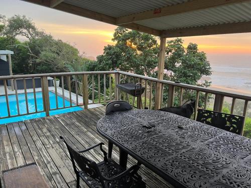a table on a deck with a view of the ocean at Linga Futhi Beach Cottages in Port St Johns