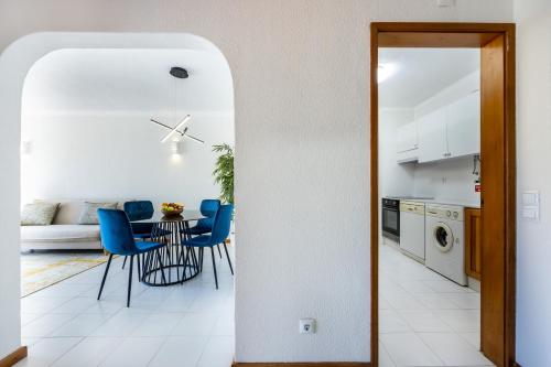 a kitchen and dining room with a table and blue chairs at Apartment Henry Matisse, swimming pool in Sagres
