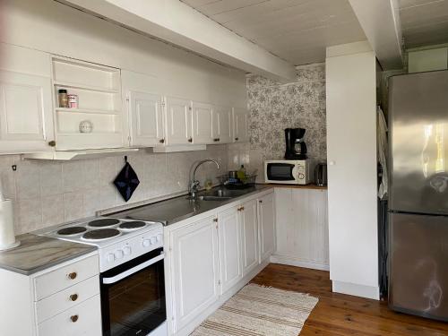 a kitchen with white cabinets and a stainless steel refrigerator at Tofta stugan in Tofta