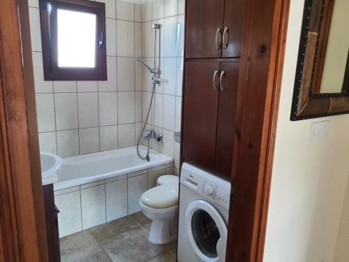 a bathroom with a toilet and a washing machine at JOANNA SUNSET APTS Pomos in Pomos