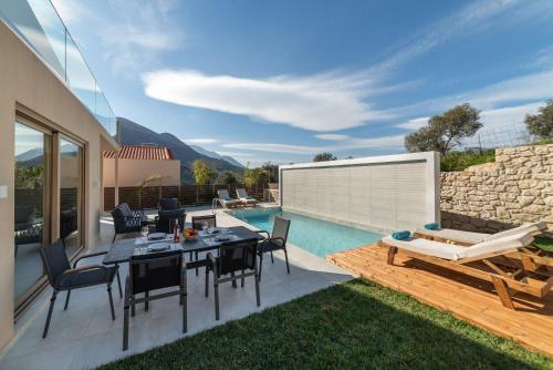 a patio with a table and chairs and a swimming pool at Villa Silentium Ionia by PosarelliVillas in Aryiroúpolis