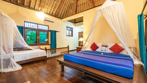 a bedroom with two beds with mosquito nets at Alam Gili Trawangan by Mahaputra in Gili Trawangan