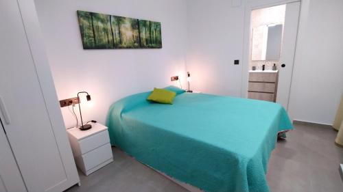 ein weißes Schlafzimmer mit einem blauen Bett und einem Fenster in der Unterkunft Apartamentos Tamarindo Santa Pola in Santa Pola