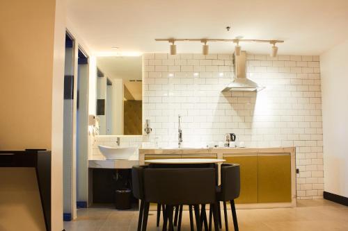 a kitchen with a sink and two black bar stools at The Blu Hotel in Baranghauon