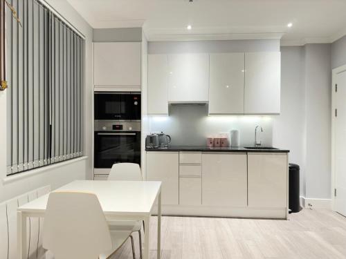 una cocina con armarios blancos y una mesa y sillas blancas. en Stylish Central London Apartment, en Londres