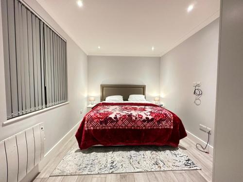 a bedroom with a bed with a red comforter at Stylish Central London Apartment in London