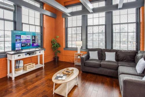 a living room with a couch and a flat screen tv at Centric Modern Loft w/ King Beds in Rochester