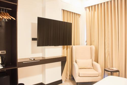 Habitación de hotel con silla y TV en The Blu Hotel, en Baranghauon